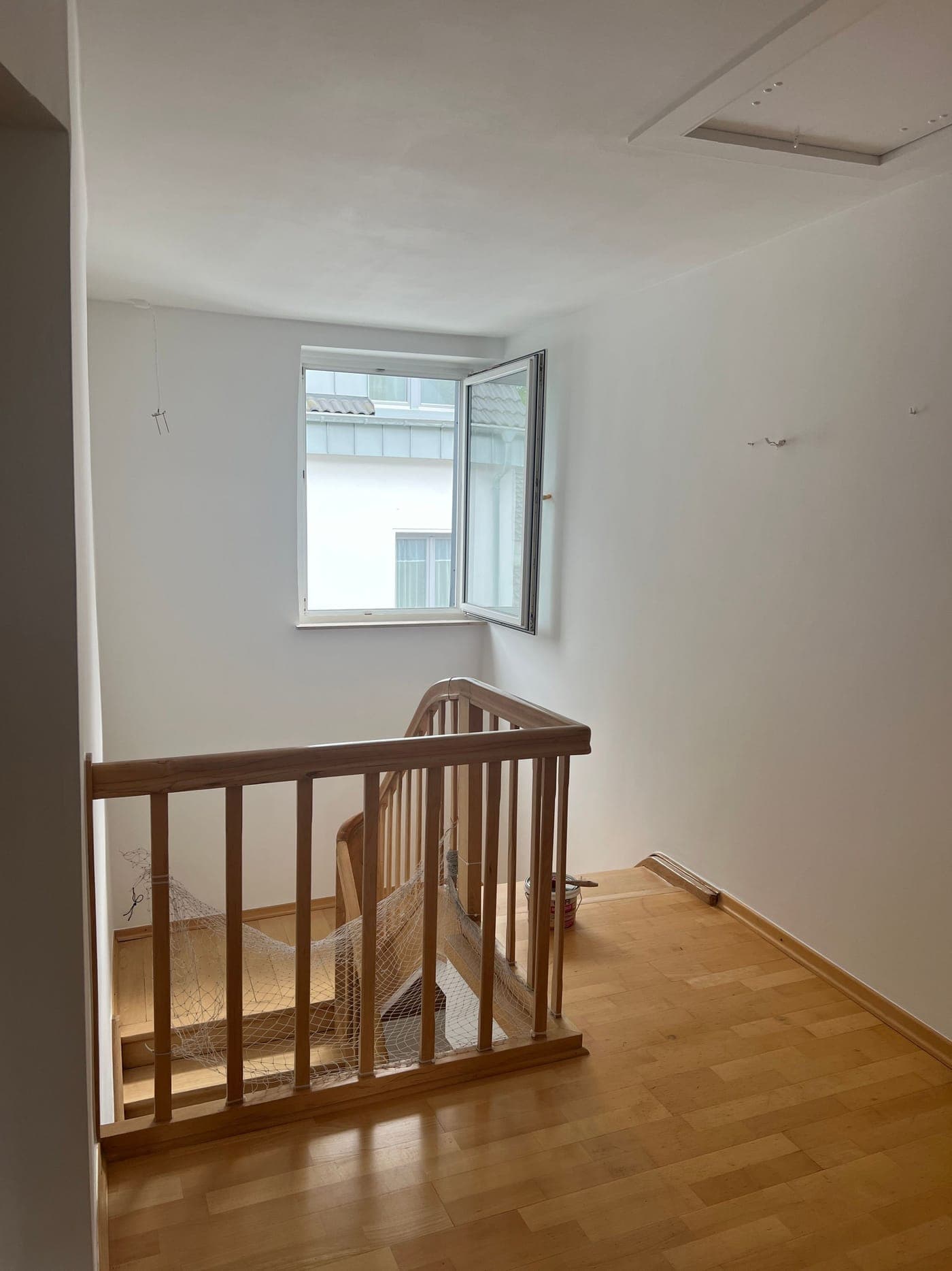 Fertig saniertes Treppenhaus mit glatten weißen Wänden und neuem Holzboden